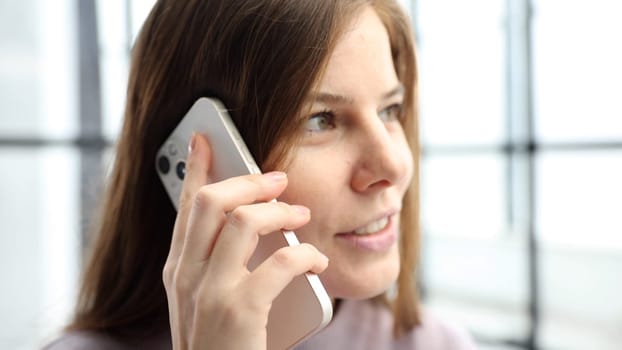 A woman's face is in close-up in the office, she is talking on the phone and discussing a business deal.