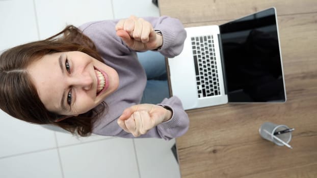 A woman in close-up in the office at a desk working with a laptop, she rejoices at a successful deal.