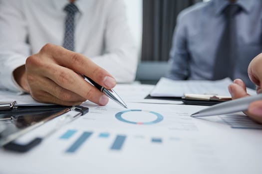 hand of a businessman shows a close-up index on the growth charts profit on the background of business documents and graphics