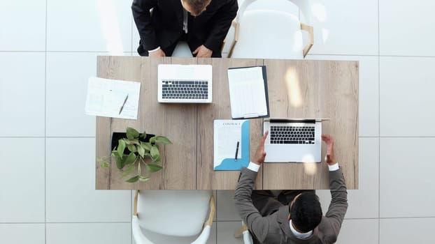 two businessmen sitting on a chair and watching something on a laptop