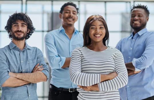 Group of professionals in businesswear, smiling and standing with arms crossed in office.