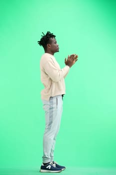 A man, full-length, on a green background, claps.