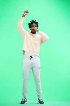 A man, full-length, on a green background, rejoices.