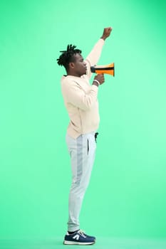 A man, full-length, on a green background, with a megaphone.