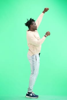 A man, full-length, on a green background, dancing.