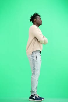 A man, full-length, on a green background, crossed his arms.