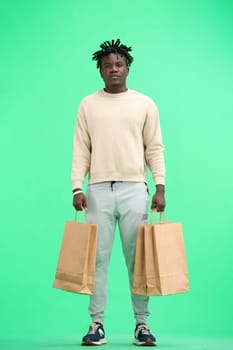 A man, full-length, on a green background, with bags.