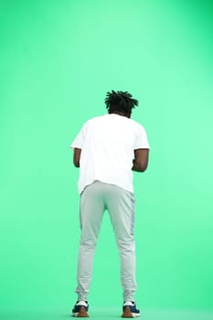 A man, full-length, on a green background, rubs his hands.