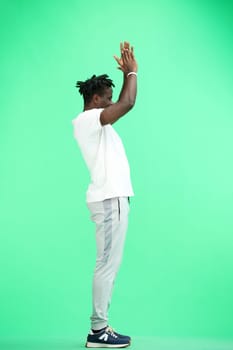 A man, full-length, on a green background, claps.