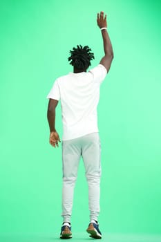 A man, full-length, on a green background, jumps.