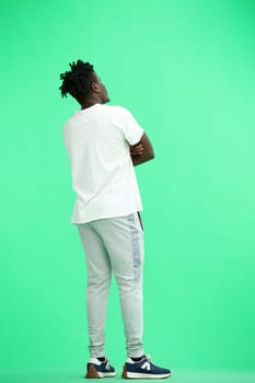A man, full-length, on a green background, crossed his arms.