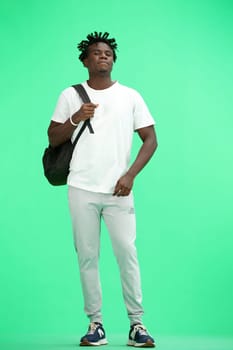 A man, full-length, on a green background, with a backpack.