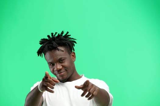 A man, close-up, on a green background, points forward.