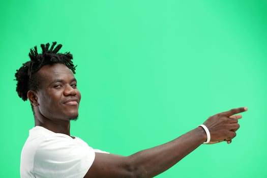 A man, close-up, on a green background, points to the side.