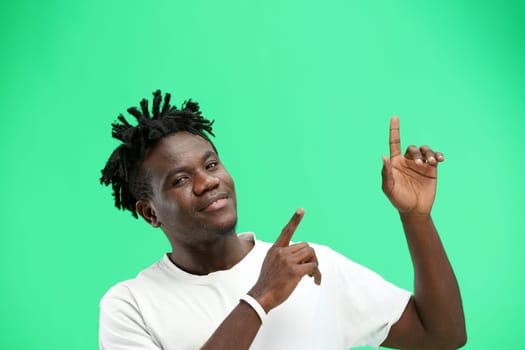 Man, close-up, on a green background, pointing up.