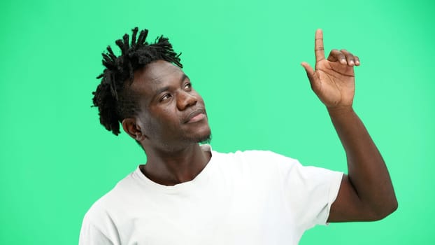 Man, close-up, on a green background, pointing up.