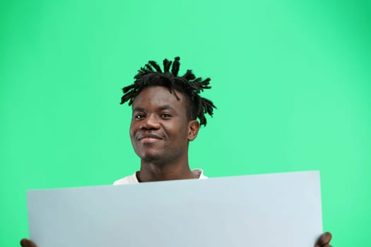 A man, close-up, on a green background, shows a white sheet.