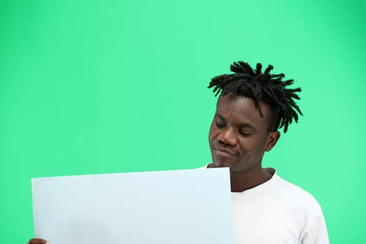 A man, close-up, on a green background, shows a white sheet.