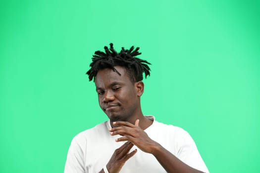 A man, close-up, on a green background, shows a pause sign.