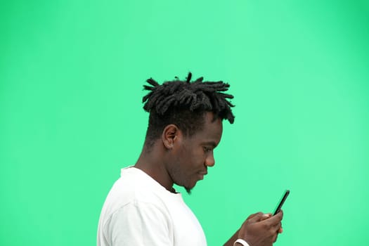 Man, close-up, on a green background, using a phone.