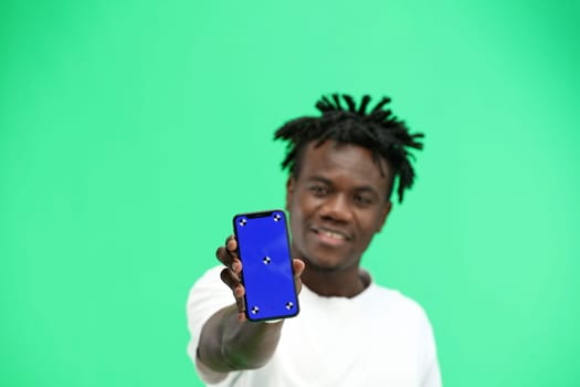 A man, close-up, on a green background, shows a phone.