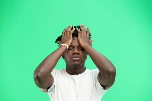 A man, close-up, on a green background, clutched his head.