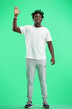A man, full-length, on a green background, waving his hand.