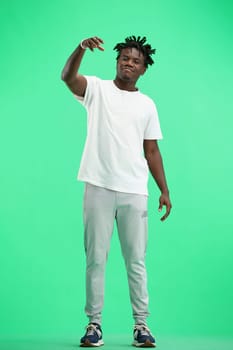 A man, full-length, on a green background, raised his hand up.