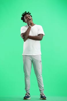 A man, full-length, on a green background, yawns.