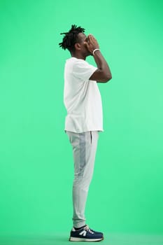 A man, full-length, on a green background, clutched his head.