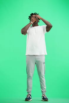 A man, full-length, on a green background, yawns.