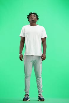 A man, full-length, on a green background, meditating.
