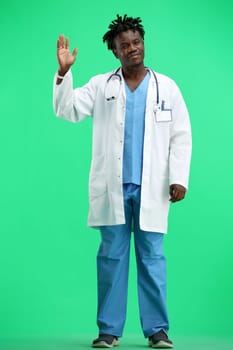 The doctor, in full height, on a green background, waving his hand.