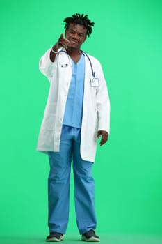 The doctor, in full height, on a green background, points forward.