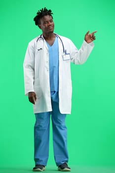 The doctor, in full height, on a green background, points to the side.