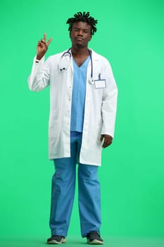 The doctor, in full height, on a green background, shows a victory sign.