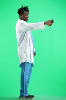 The doctor, in full height, on a green background, talking on the phone.