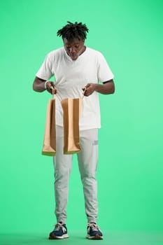 A man, full-length, on a green background, with bags.