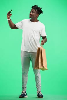 A man, full-length, on a green background, with bags.