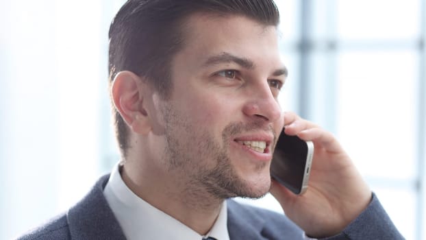 A businessman man in close-up in the office talking on the phone.