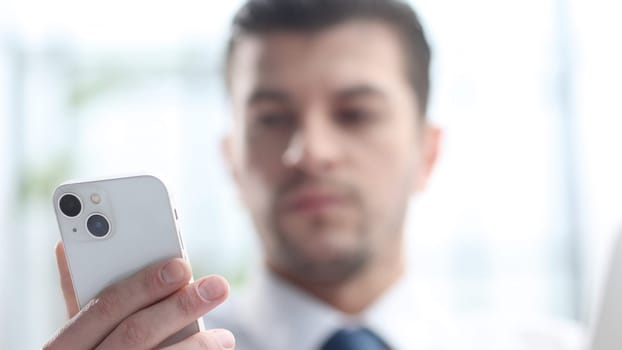 A male businessman uses a phone in close-up.