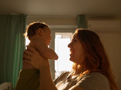 A Caucasian woman tenderly holds her newborn son in the morning rays of sunlight