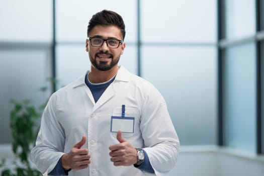 Handsome male doctor in white coat with thumbs up. Clinic