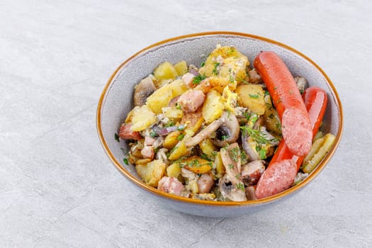 fried potatoes with mushrooms and sausages on a stone background studio food photo