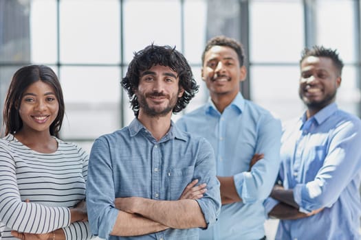 Group of professionals in businesswear, smiling and standing with arms crossed in office.