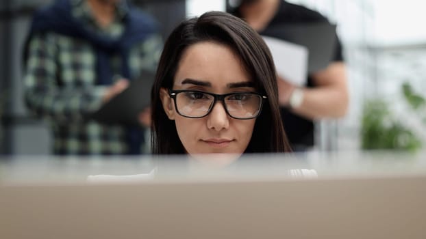 Confident business woman in casual clothes sitting in the office and working on a laptop