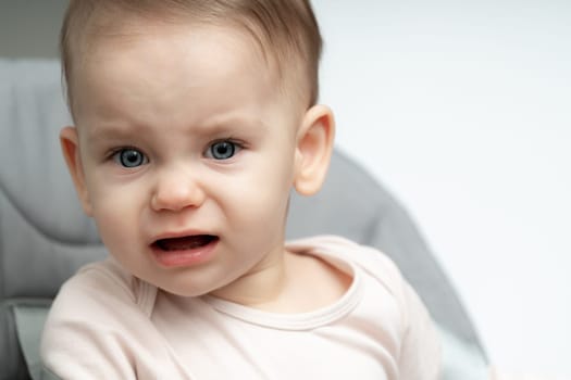 Portrait of crying 1-year old baby upset of being hungry and tired with copy space