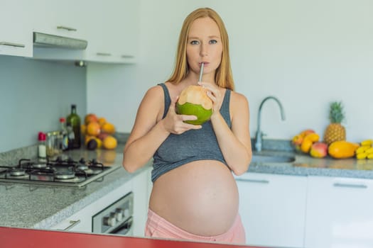 Quenching her pregnancy thirst with a refreshing choice, a pregnant woman joyfully drinks coconut water from a coconut in the kitchen, embracing natural hydration during this special journey.