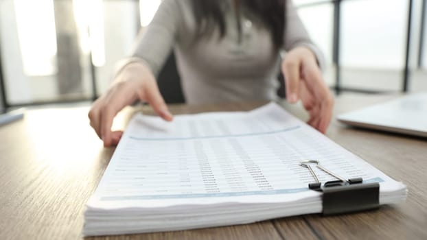 A young woman in the office is working with documents and reports.
