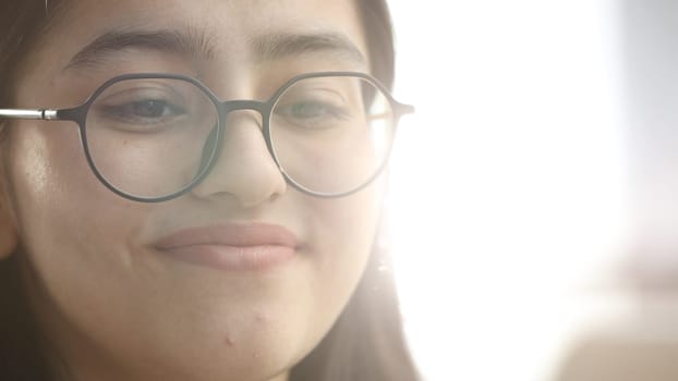 A young woman with glasses in the office is working with a laptop.
